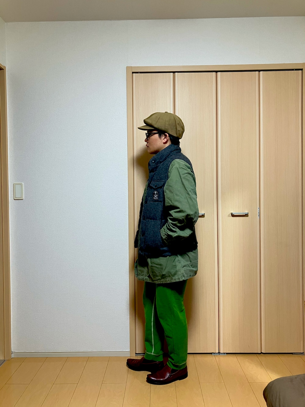 グリーン系のミリタリージャケット、グレー系のダウンベスト、グリーン系のスウェットパンツを着用したメンズの冬コーディネートの2枚目の写真