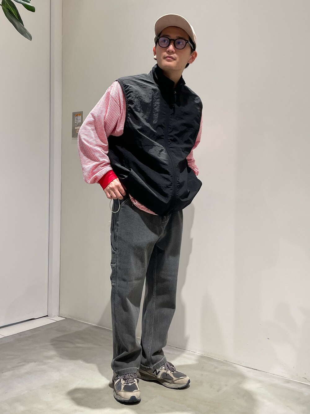 ブラック系のベスト、ブラック系のデニムパンツ、グレー系のスニーカーを着用したメンズの秋コーディネートの2枚目の写真