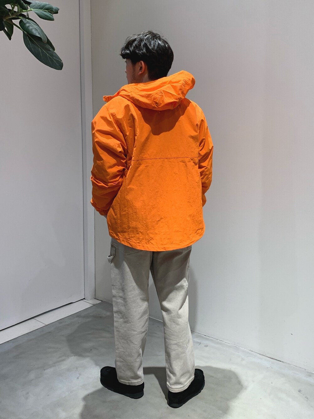 ブラック系のモカシン/デッキシューズ、ベージュ系のデニムパンツ、オレンジ系のマウンテンパーカーを着用したメンズの春コーディネートの2枚目の写真