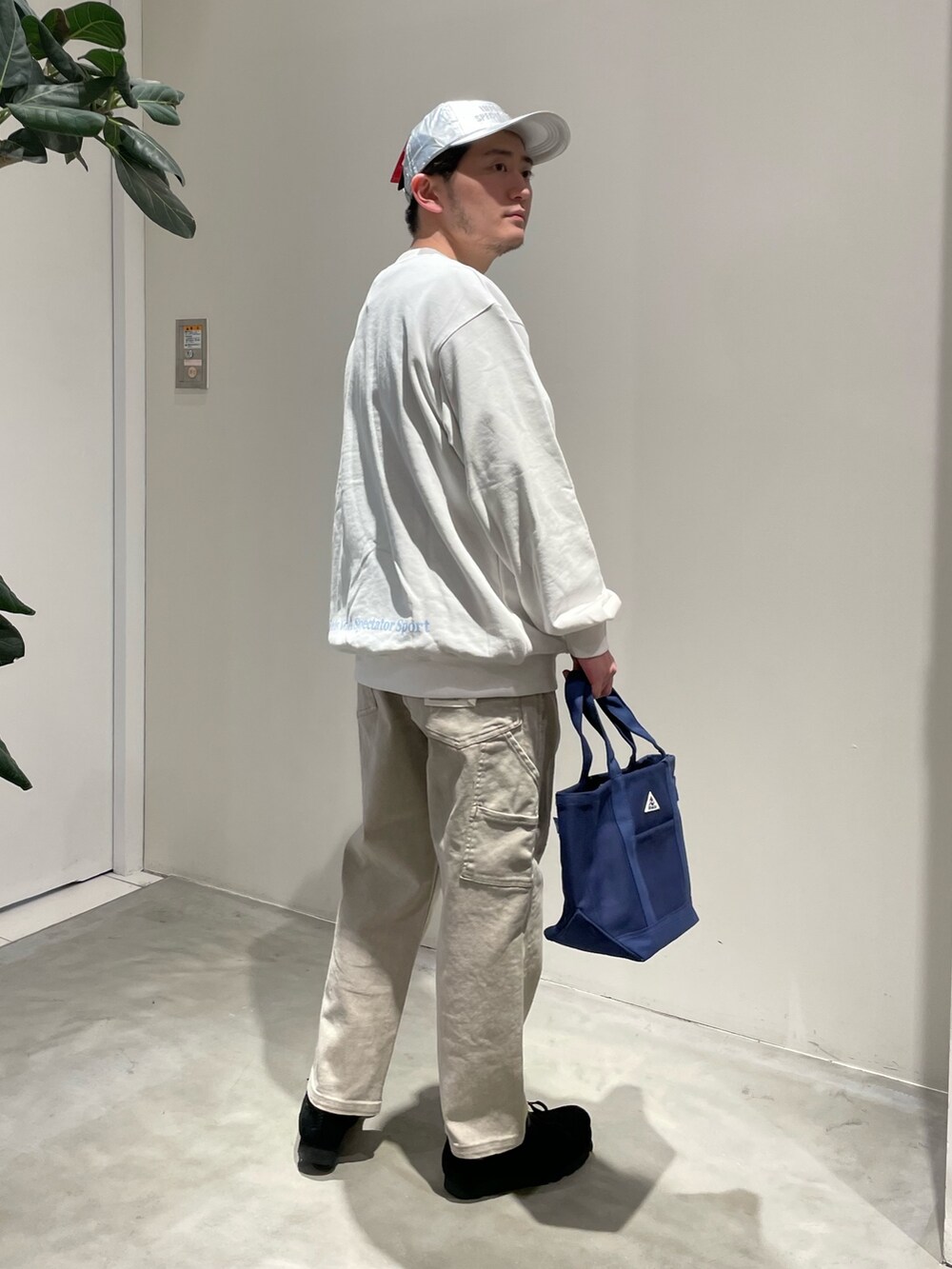 ホワイト系のスウェット、ベージュ系のデニムパンツ、ブルー系のトートバッグを着用したメンズの春コーディネートの2枚目の写真