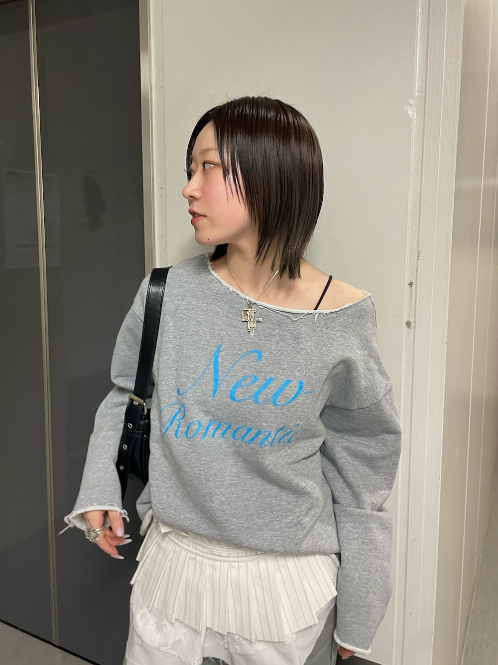 グレー系のスウェット、ブラック系のパンプス、ホワイト系のベルトを着用したレディースの春コーディネートの2枚目の写真