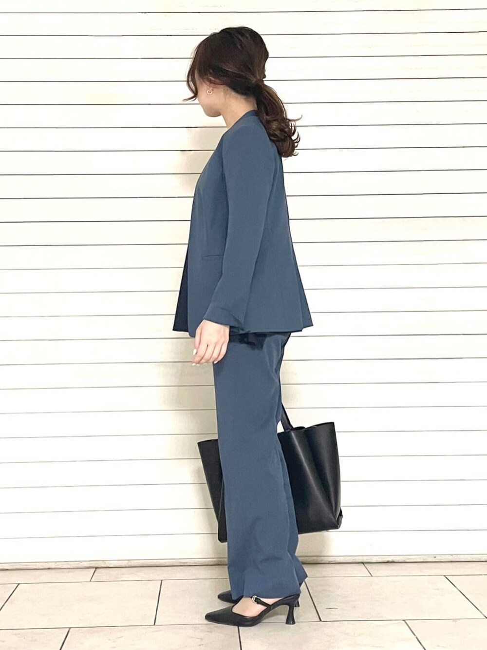 ブルー系のスーツパンツ、ブラック系のトートバッグ、ブルー系のシャツ/ブラウスを着用したレディースの春コーディネートの3枚目の写真