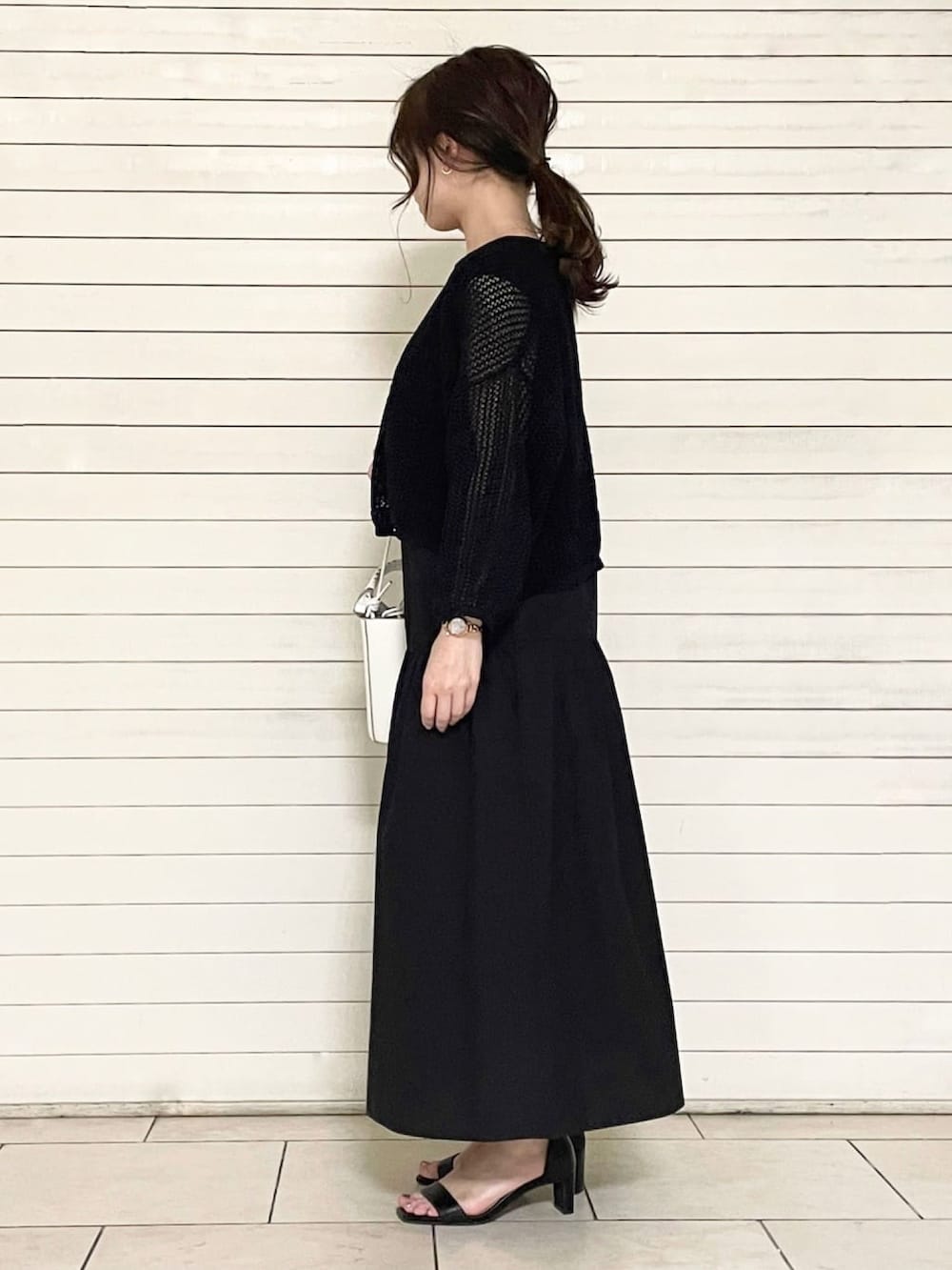 ブラック系のサンダル、ホワイト系のショルダーバッグ、ブラック系のセットアップを着用したレディースの春コーディネートの2枚目の写真