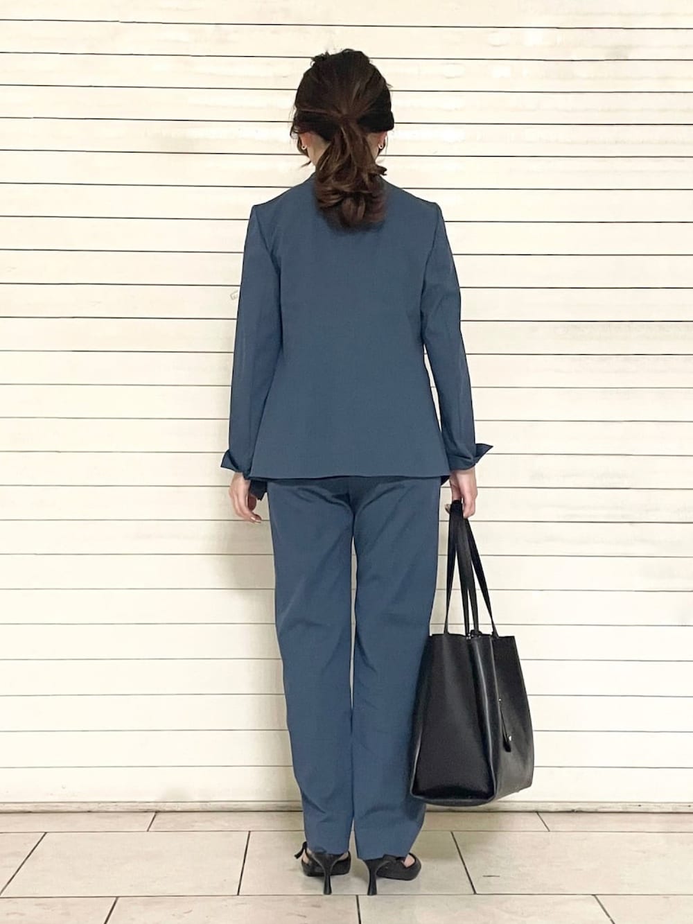 ブルー系のスーツパンツ、ブラック系のトートバッグ、ブルー系のシャツ/ブラウスを着用したレディースの春コーディネートの2枚目の写真