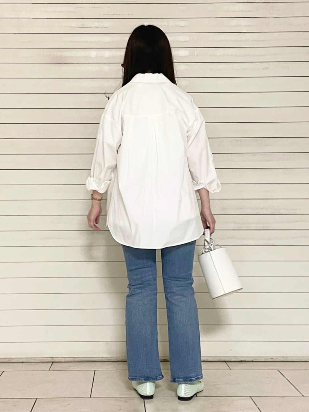 ブルー系のデニムパンツ、グリーン系のパンプス、ホワイト系のショルダーバッグを着用したレディースの夏コーディネートの3枚目の写真