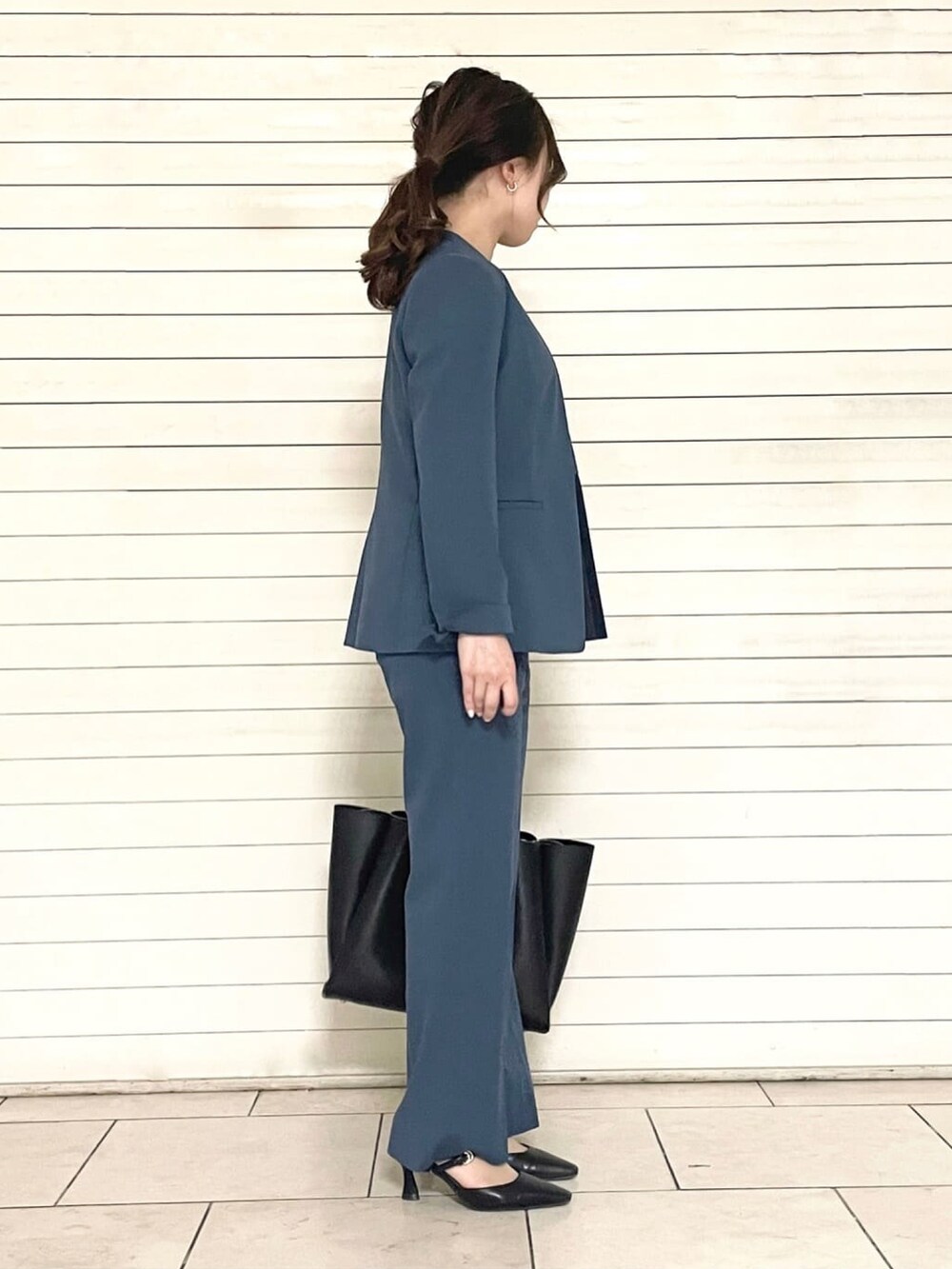 ブルー系のスーツパンツ、ブラック系のトートバッグ、ブルー系のシャツ/ブラウスを着用したレディースの春コーディネートの4枚目の写真