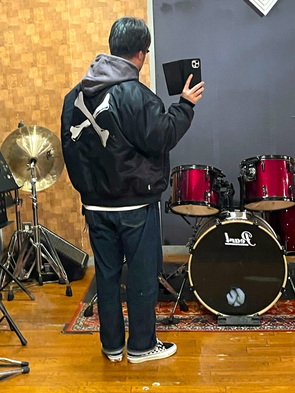 ブラック系のナイロンジャケット、ブラウン系のパーカー、ブルー系のデニムパンツを着用したメンズの春コーディネートの3枚目の写真