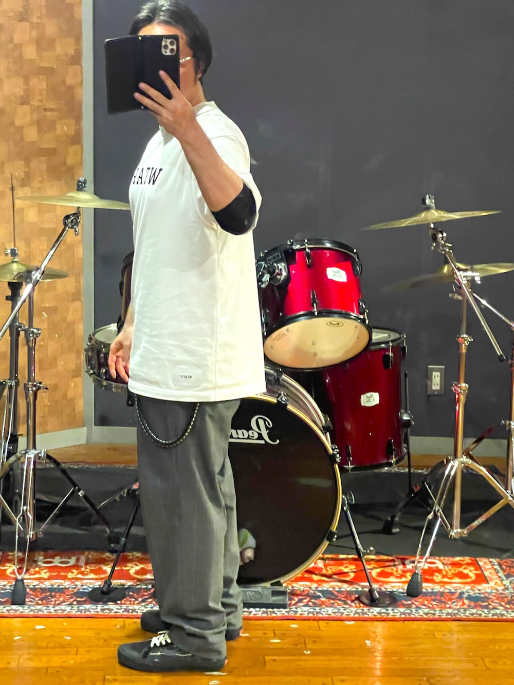 ホワイト系のTシャツ/カットソー、グレー系のスラックス、ブラック系のスニーカーを着用したメンズの夏コーディネートの4枚目の写真