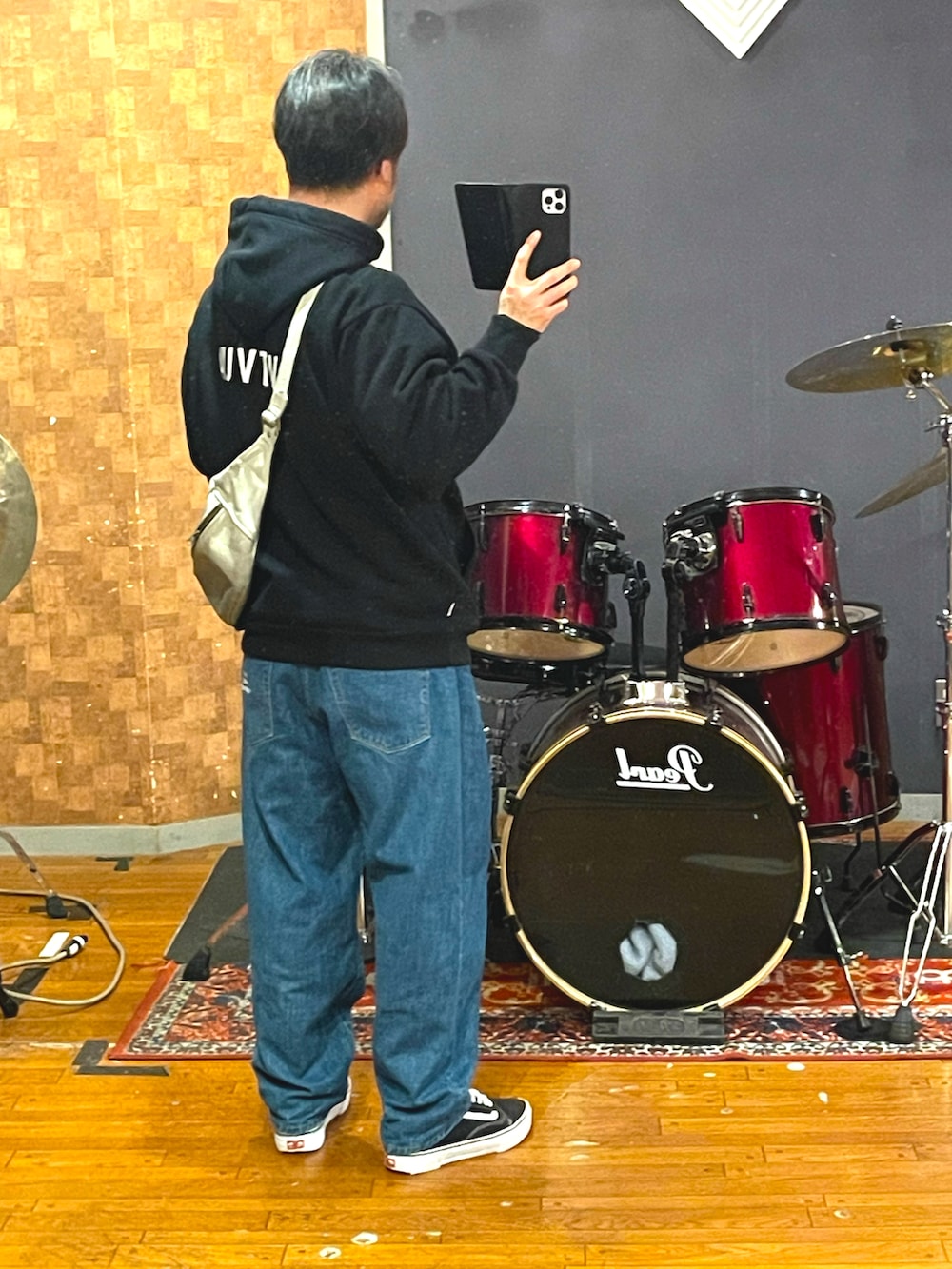 ブラック系のパーカー、ブルー系のデニムパンツ、ブラック系のスニーカーを着用したメンズの春コーディネートの2枚目の写真