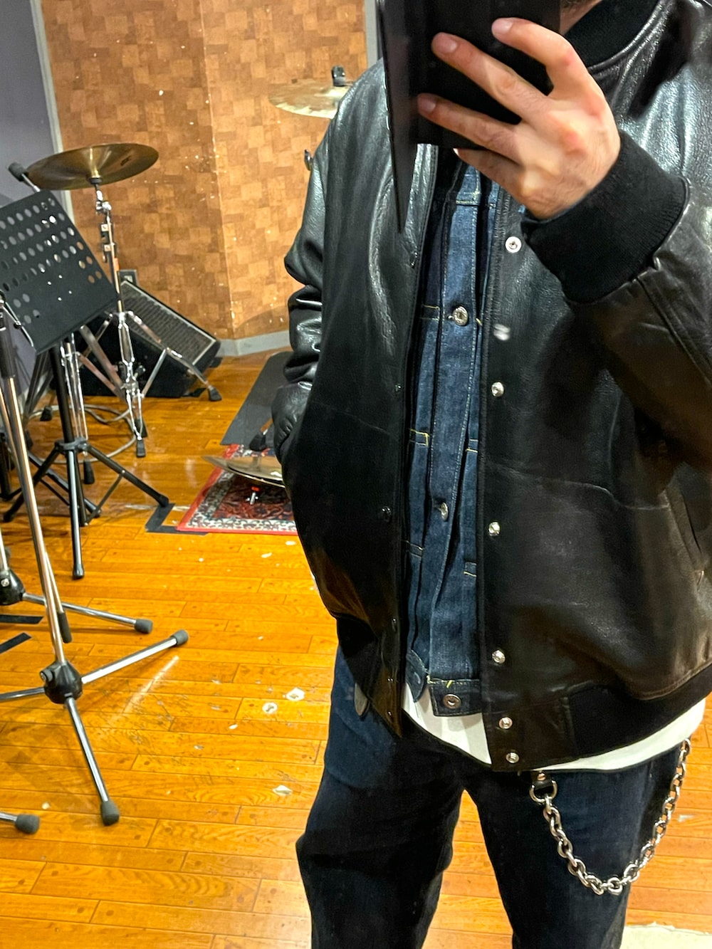 ブラック系のスタジャン、ブルー系のデニムパンツ、ホワイト系のスニーカーを着用したメンズの秋コーディネートの3枚目の写真