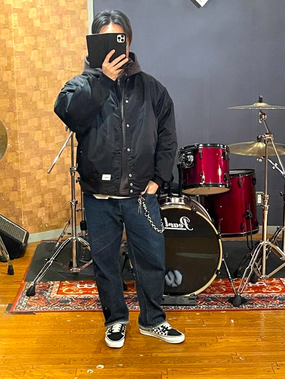 ブラック系のナイロンジャケット、ブラウン系のパーカー、ブルー系のデニムパンツを着用したメンズの春コーディネートの4枚目の写真