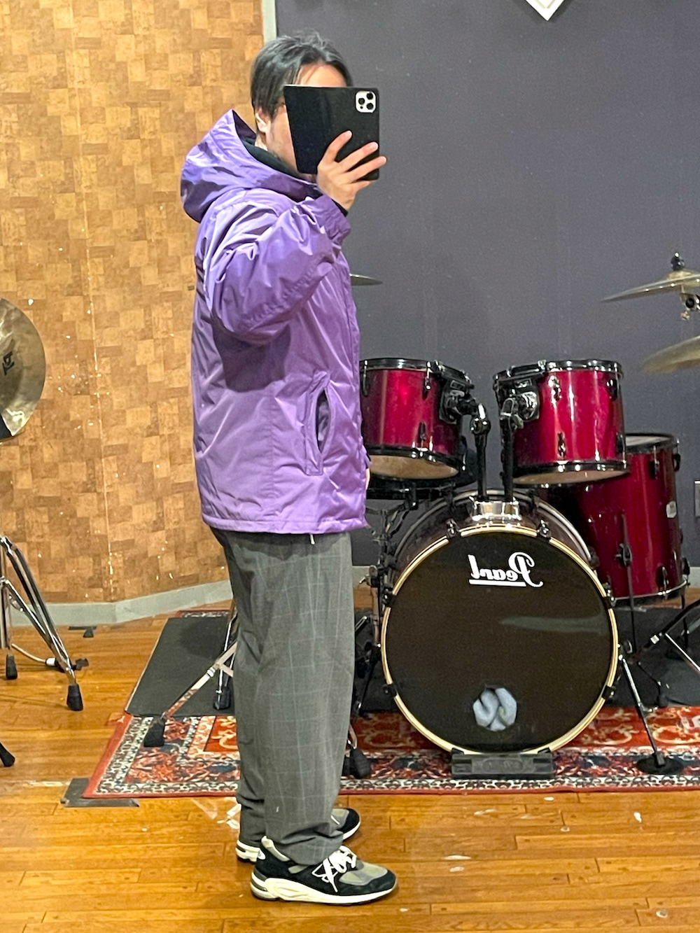 パープル系のマウンテンパーカー、ブラック系のパーカー、グレー系のスラックスを着用したメンズの春コーディネートの3枚目の写真