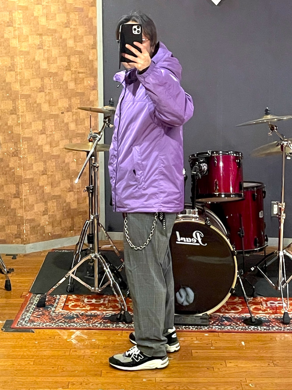 パープル系のマウンテンパーカー、ブラック系のパーカー、グレー系のスラックスを着用したメンズの春コーディネートの2枚目の写真