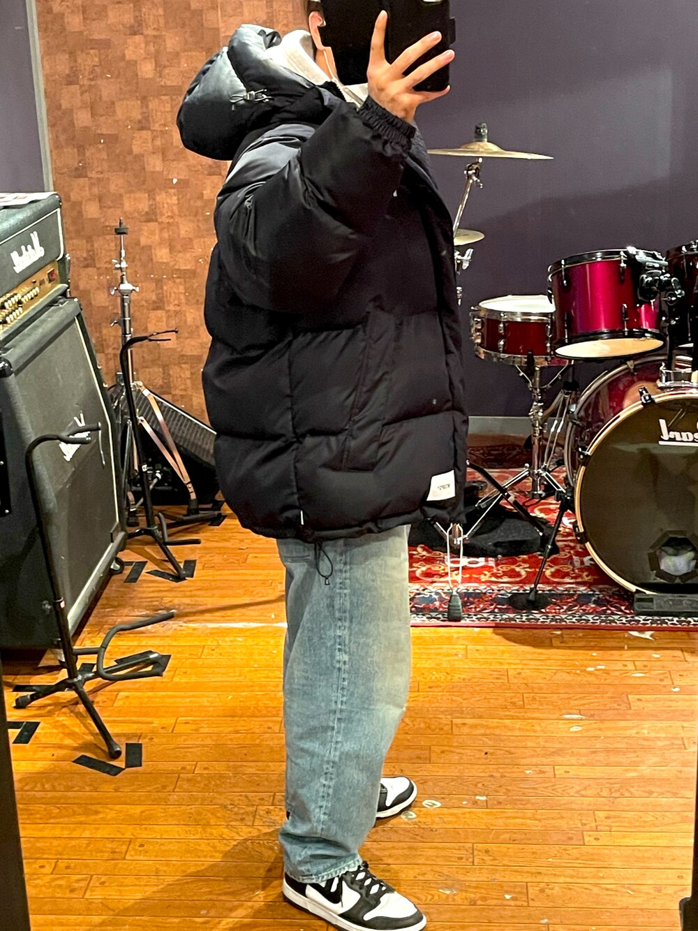 ブラック系のダウンジャケット/コート、グレー系のパーカー、ブルー系のデニムパンツを着用したメンズの冬コーディネートの2枚目の写真