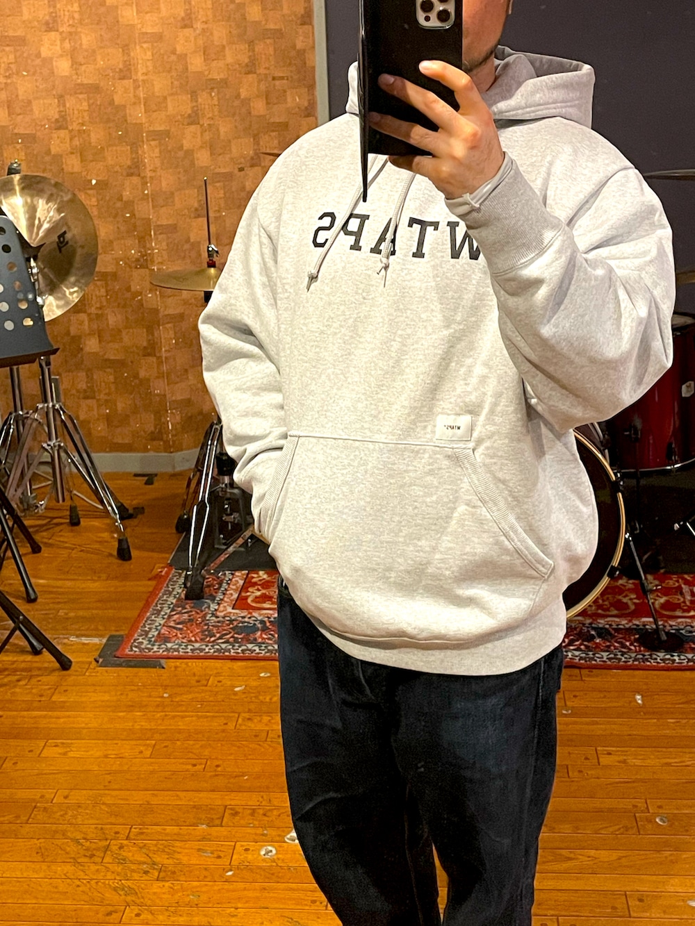 グレー系のパーカー、ブルー系のデニムパンツ、ブラック系のスニーカーを着用したメンズの春コーディネートの2枚目の写真