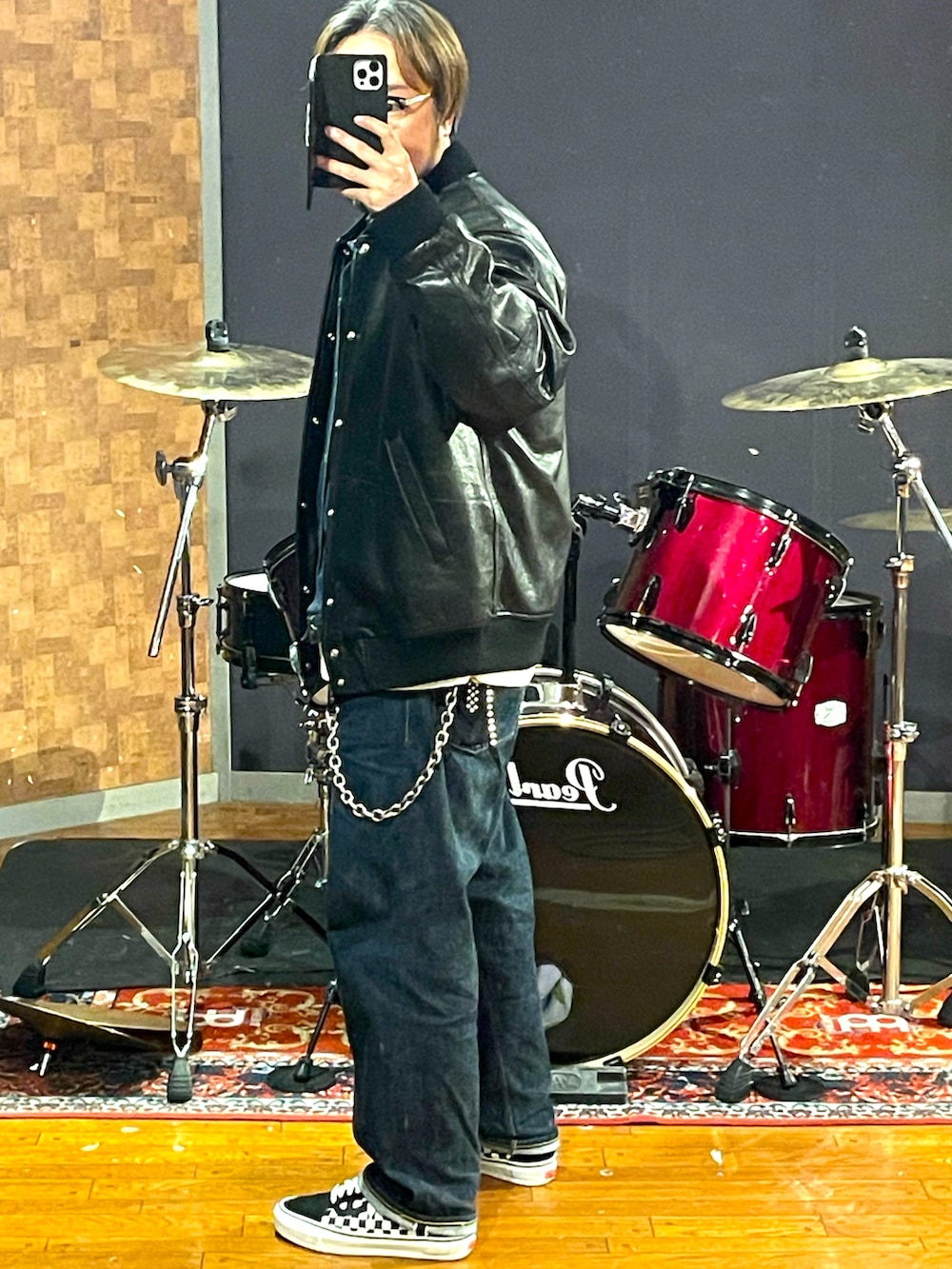 ブラック系のスタジャン、ブルー系のデニムパンツ、ホワイト系のスニーカーを着用したメンズの秋コーディネートの2枚目の写真