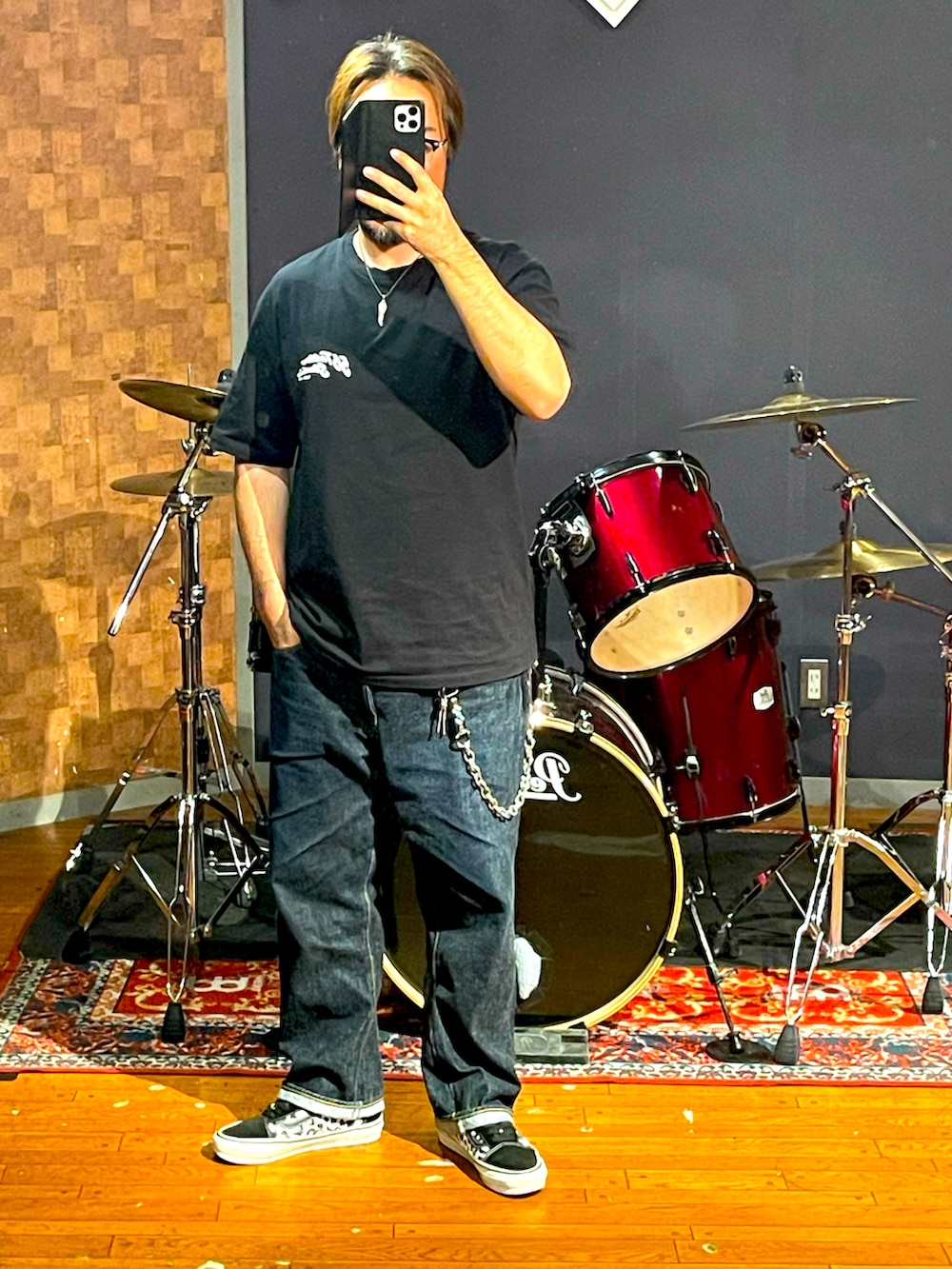 ブラック系のTシャツ/カットソー、ブルー系のデニムパンツ、ブラック系のスニーカーを着用したメンズの秋コーディネートの5枚目の写真