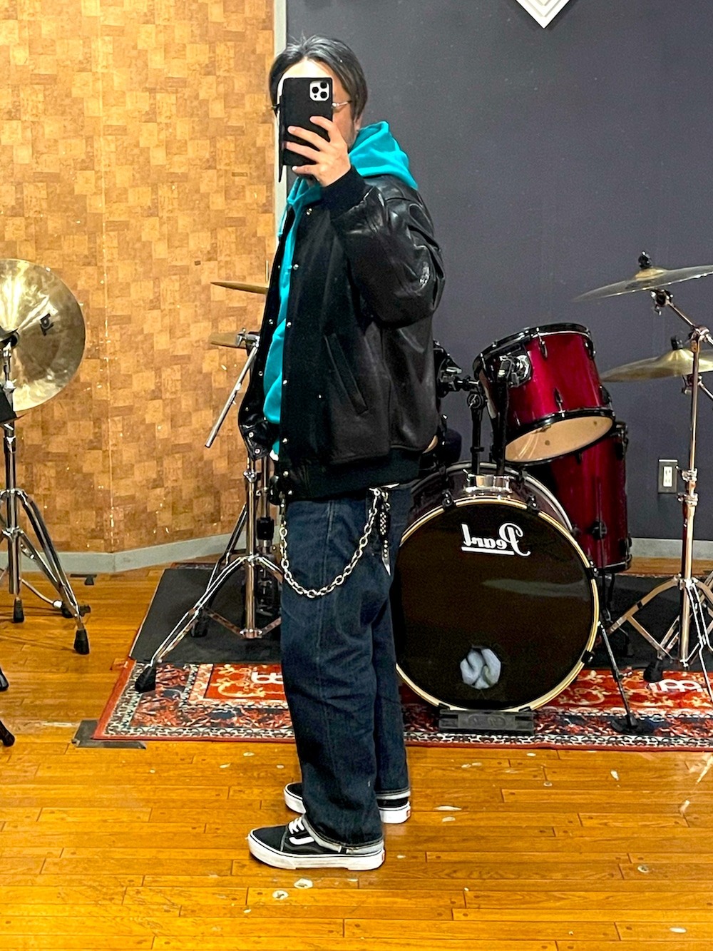 ブラック系のスタジャン、グリーン系のパーカー、ブルー系のデニムパンツを着用したメンズの春コーディネートの2枚目の写真