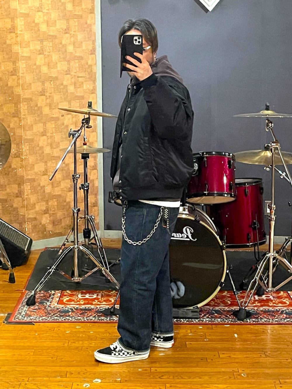 ブラック系のナイロンジャケット、ブラウン系のパーカー、ブルー系のデニムパンツを着用したメンズの春コーディネートの2枚目の写真