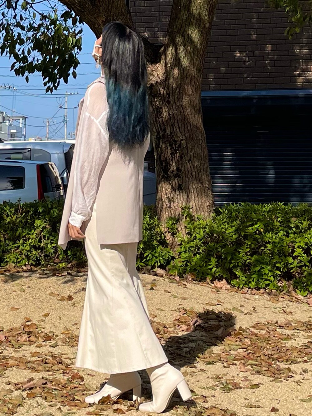 ホワイト系のベスト、ホワイト系のスカート、ホワイト系のブーツを着用したレディースの春コーディネートの2枚目の写真