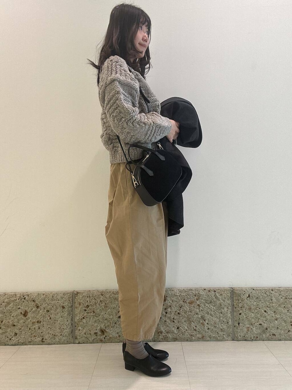 グレー系のニット/セーター、ブラック系のショルダーバッグ、ブラック系のその他シューズを着用したレディースの秋コーディネートの2枚目の写真