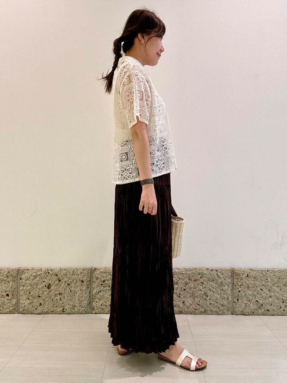 ホワイト系のハンドバッグ、ホワイト系のタンクトップ、ブラウン系のスカートを着用したレディースの夏コーディネートの3枚目の写真