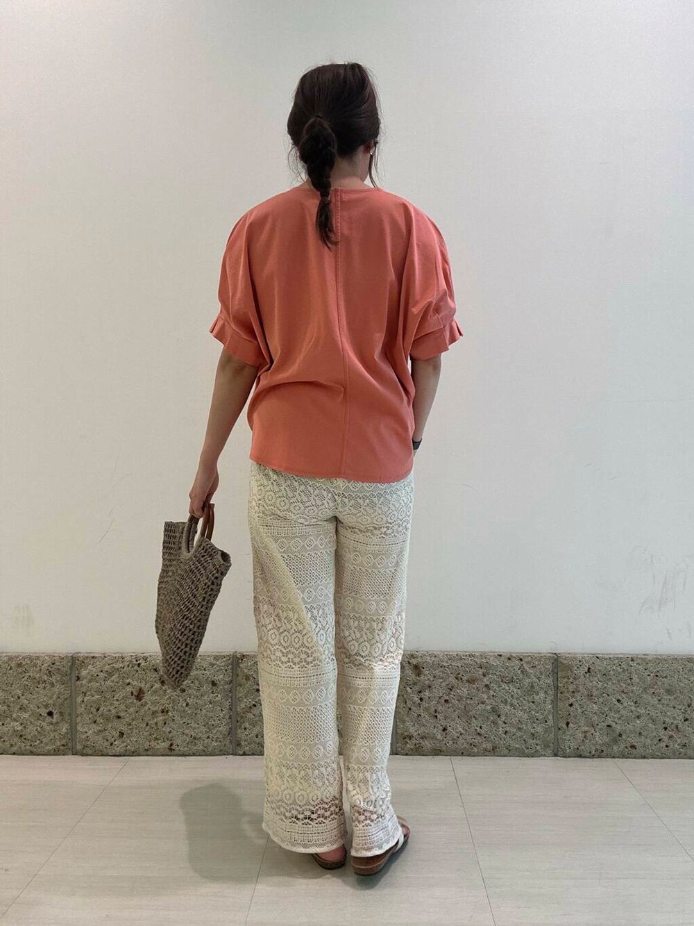 グレー系のトートバッグ、ホワイト系のその他パンツ、オレンジ系のTシャツ/カットソーを着用したレディースの夏コーディネートの3枚目の写真
