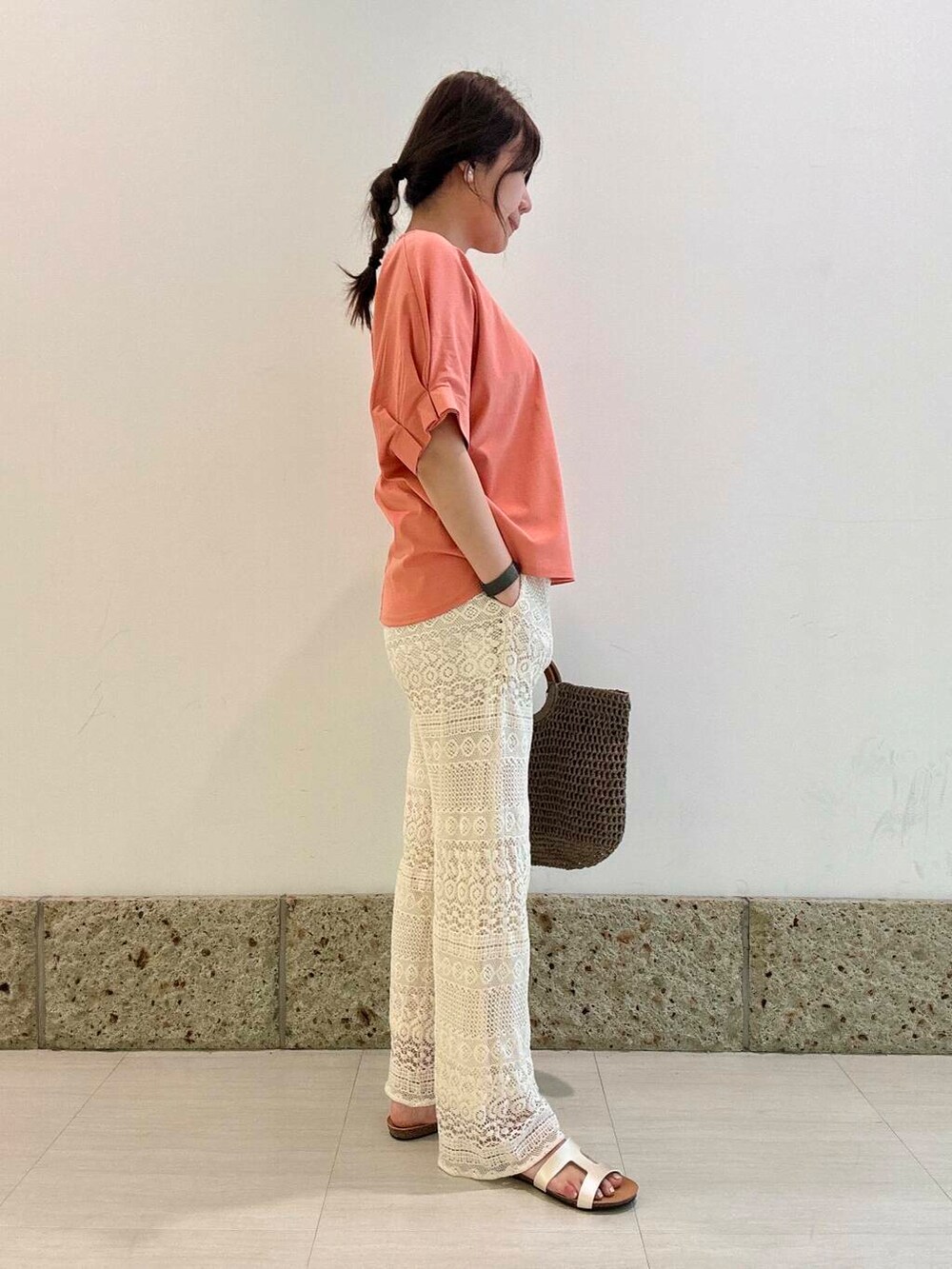 グレー系のトートバッグ、ホワイト系のその他パンツ、オレンジ系のTシャツ/カットソーを着用したレディースの夏コーディネートの2枚目の写真