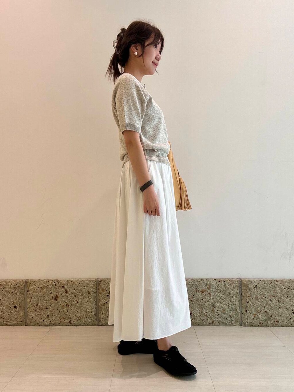 ベージュ系のトートバッグ、ホワイト系のスカート、ベージュ系のニット/セーターを着用したレディースの春コーディネートの2枚目の写真