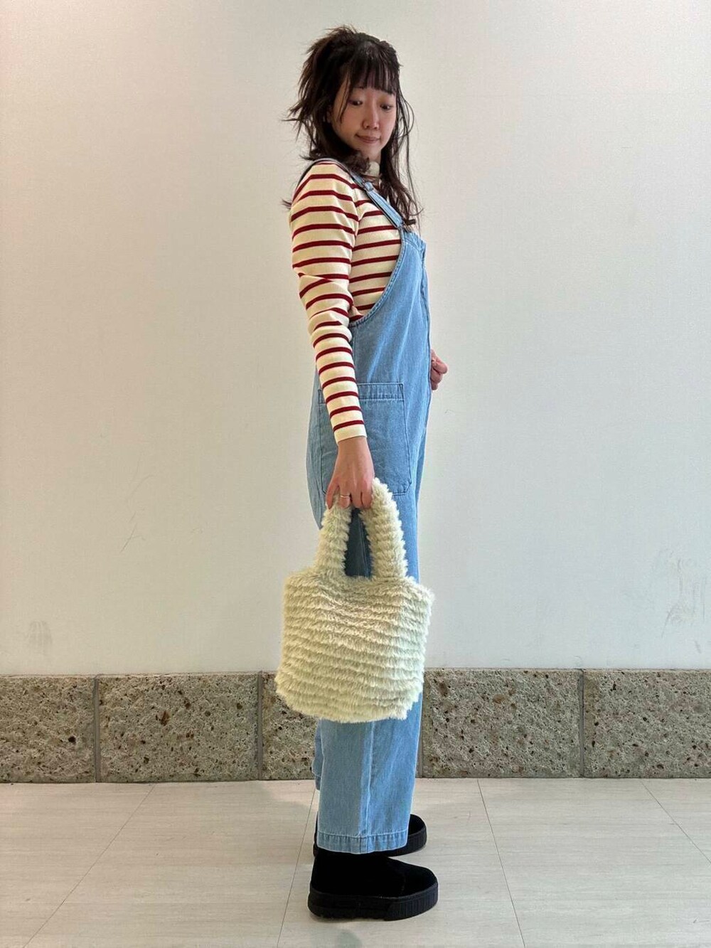 ブラック系のブーツ、グリーン系のトートバッグ、ブルー系のサロペット/オーバーオールを着用したレディースの冬コーディネートの2枚目の写真