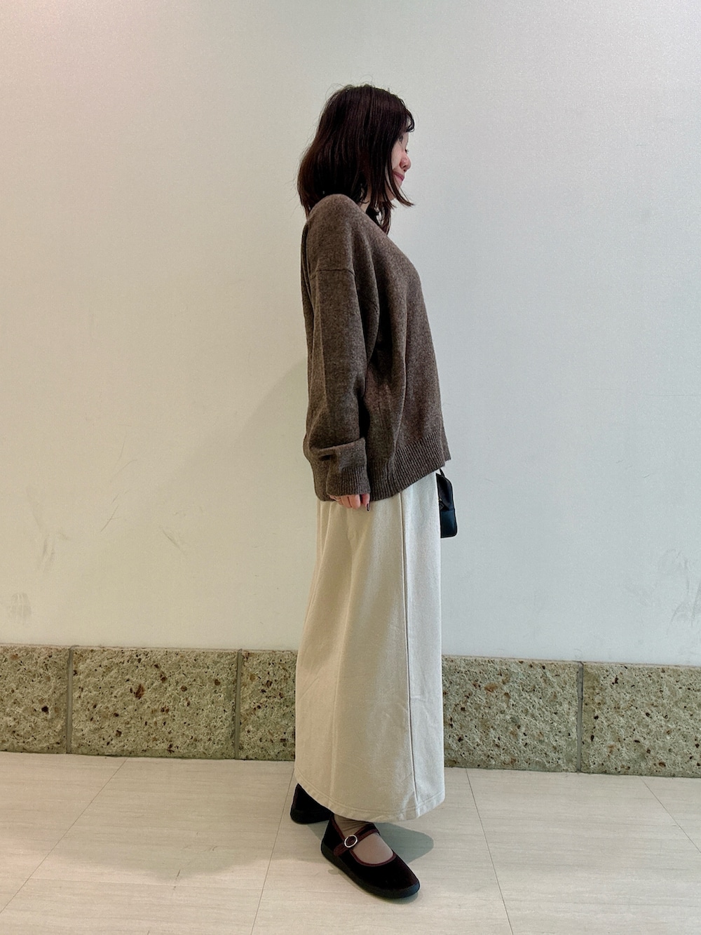 ブラック系のボストンバッグ、ブラウン系のニット/セーター、ベージュ系のスカートを着用したレディースの秋コーディネートの2枚目の写真