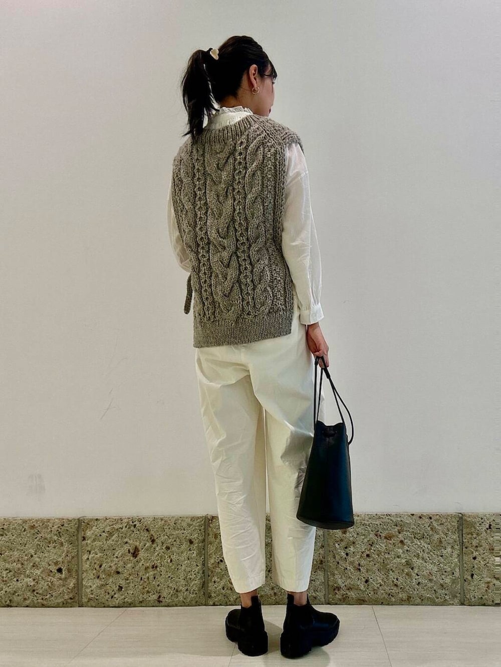 グレー系のニット/セーター、ブラック系のショルダーバッグ、ブラック系のブーツを着用したレディースの秋コーディネートの3枚目の写真