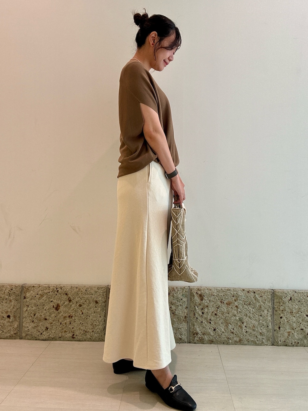 イエロー系のニット/セーター、ホワイト系のスカート、ブラック系のパンプスを着用したレディースの秋コーディネートの3枚目の写真