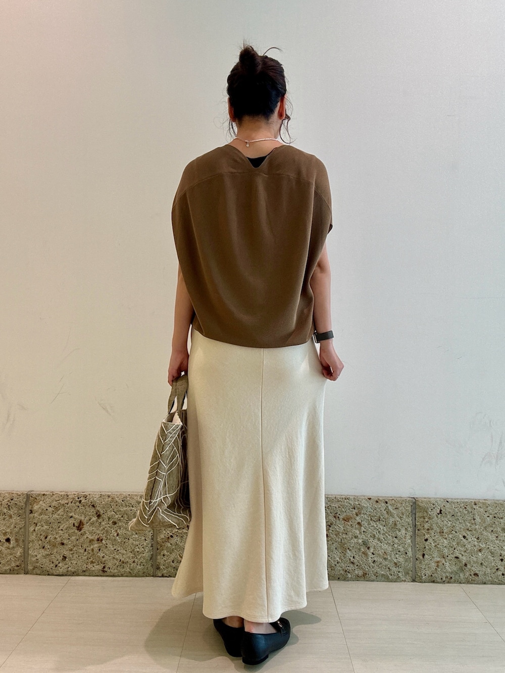 イエロー系のニット/セーター、ホワイト系のスカート、ブラック系のパンプスを着用したレディースの秋コーディネートの5枚目の写真