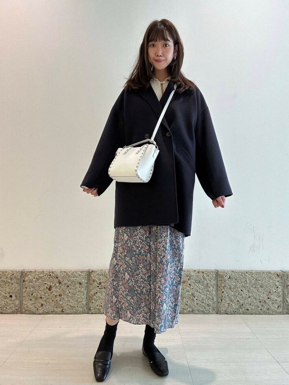 ブラック系のローファー、ブルー系のその他アウター、ホワイト系のショルダーバッグを着用したレディースの冬コーディネートの2枚目の写真