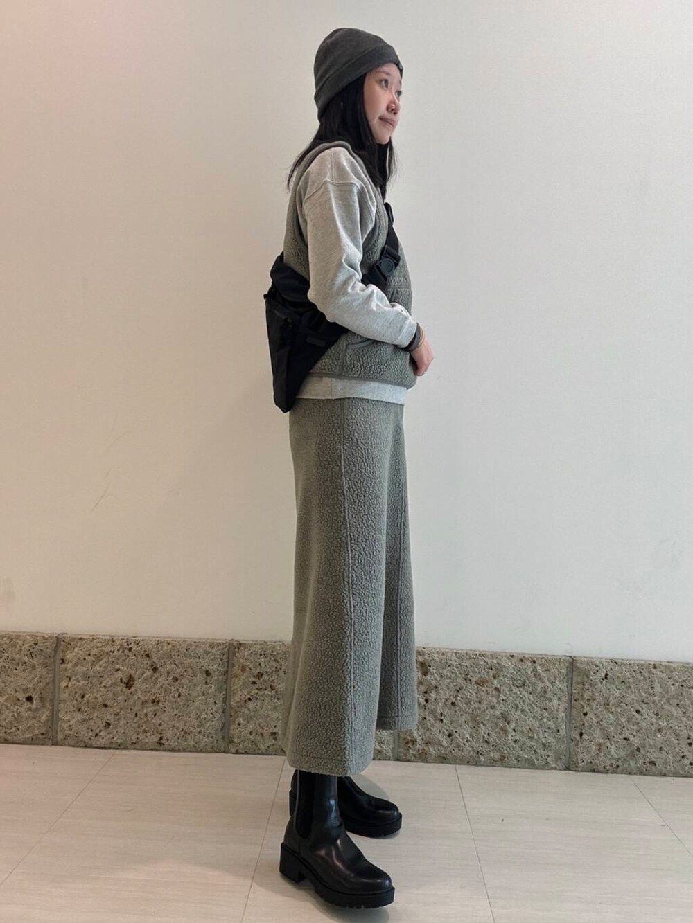 ブラック系のブーツ、ブラック系のショルダーバッグ、グレー系のベストを着用したレディースの秋コーディネートの2枚目の写真