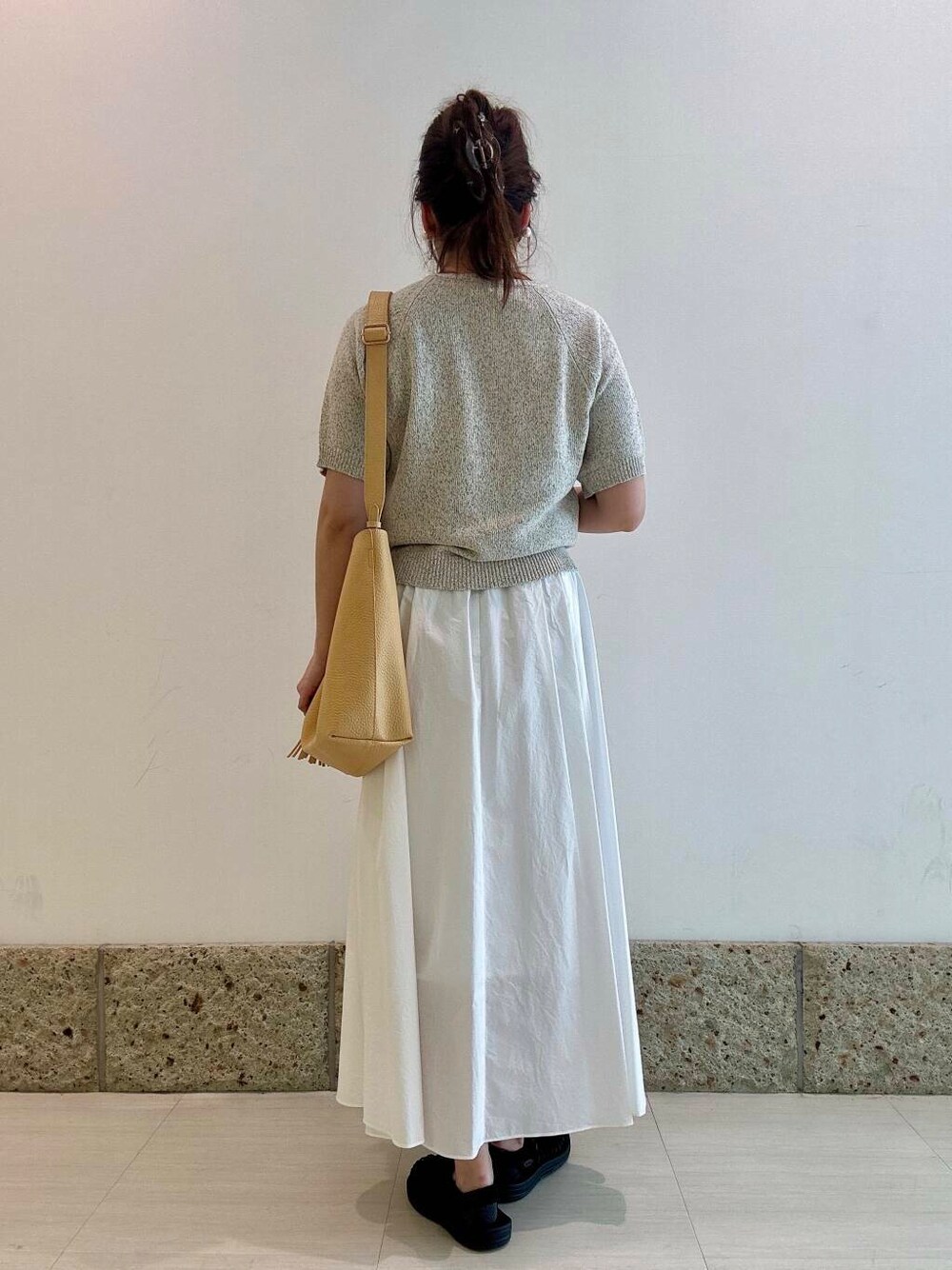 ベージュ系のトートバッグ、ホワイト系のスカート、ベージュ系のニット/セーターを着用したレディースの春コーディネートの3枚目の写真