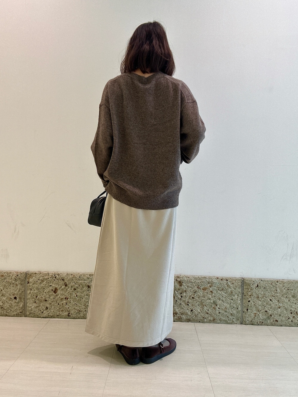 ブラック系のボストンバッグ、ブラウン系のニット/セーター、ベージュ系のスカートを着用したレディースの秋コーディネートの4枚目の写真