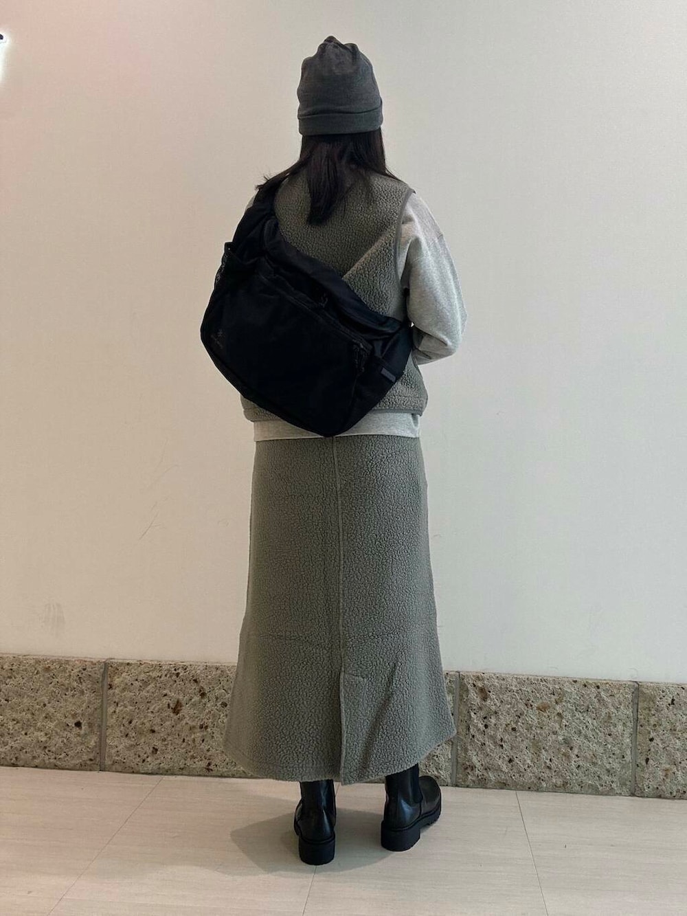 ブラック系のブーツ、ブラック系のショルダーバッグ、グレー系のベストを着用したレディースの秋コーディネートの3枚目の写真