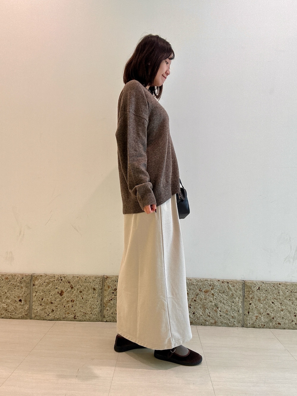 ブラック系のボストンバッグ、ブラウン系のニット/セーター、ベージュ系のスカートを着用したレディースの秋コーディネートの3枚目の写真