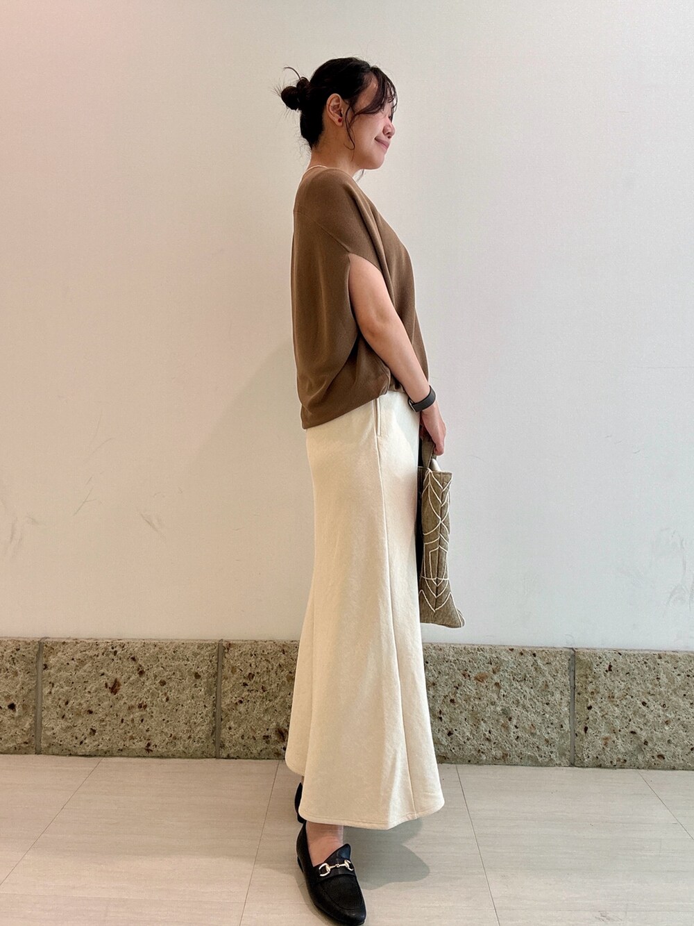 イエロー系のニット/セーター、ホワイト系のスカート、ブラック系のパンプスを着用したレディースの秋コーディネートの4枚目の写真