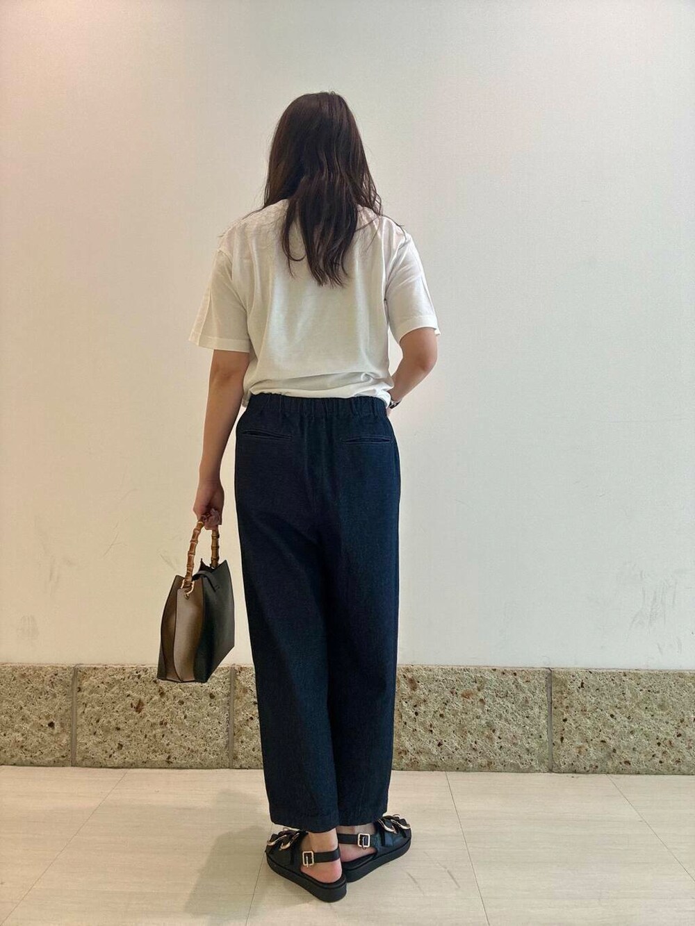 ブラック系のショルダーバッグ、ブラック系のサンダル、ホワイト系のTシャツ/カットソーを着用したレディースの夏コーディネートの3枚目の写真