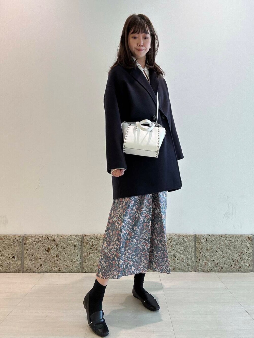 ブラック系のローファー、ブルー系のその他アウター、ホワイト系のショルダーバッグを着用したレディースの冬コーディネートの3枚目の写真