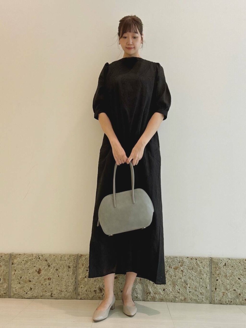 ベージュ系のパンプス、ブルー系のハンドバッグ、ブラック系のワンピースを着用したレディースの秋コーディネートの2枚目の写真