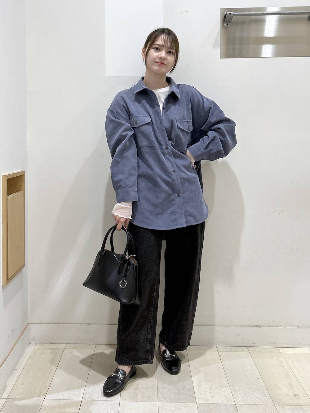 ブラック系のローファー、ブラック系のショルダーバッグ、ブラック系のデニムパンツを着用したレディースの秋コーディネートの6枚目の写真