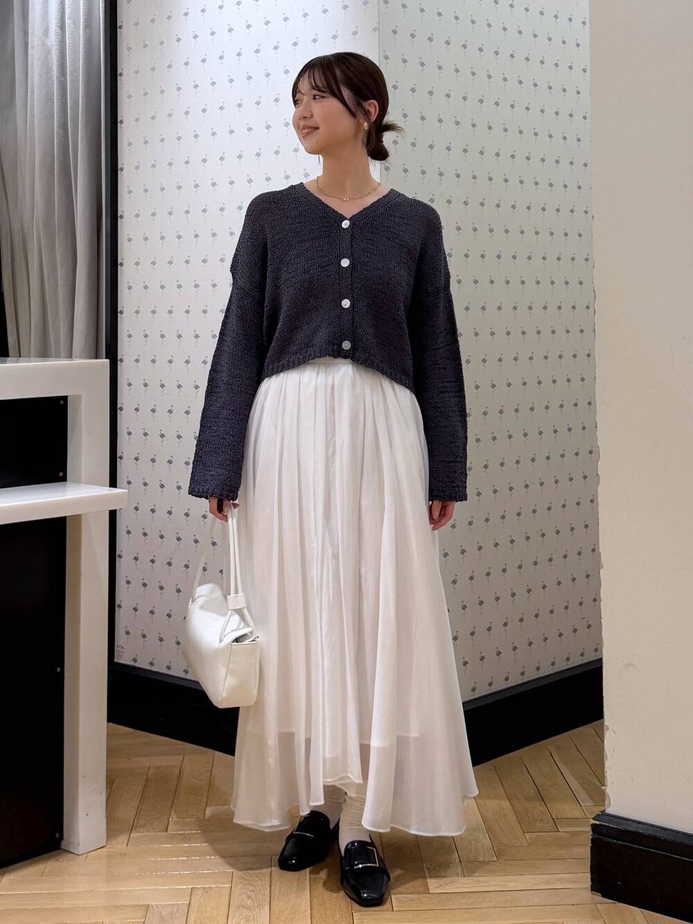 ホワイト系のスカート、ブラック系のローファー、ホワイト系のショルダーバッグを着用したレディースの冬コーディネートの3枚目の写真