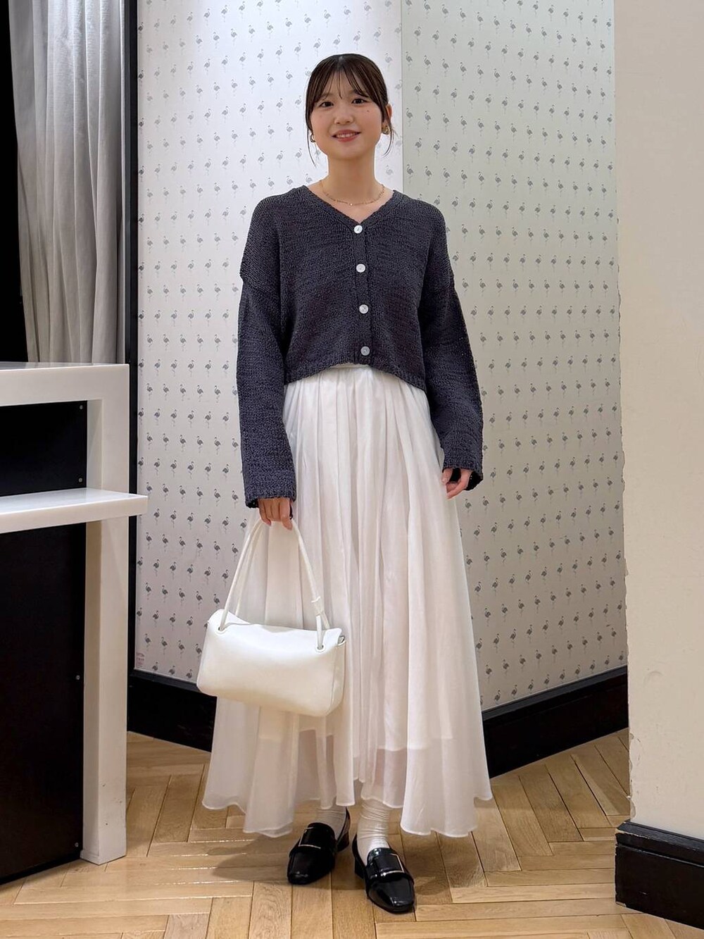 ホワイト系のスカート、ブラック系のローファー、ホワイト系のショルダーバッグを着用したレディースの冬コーディネートの2枚目の写真