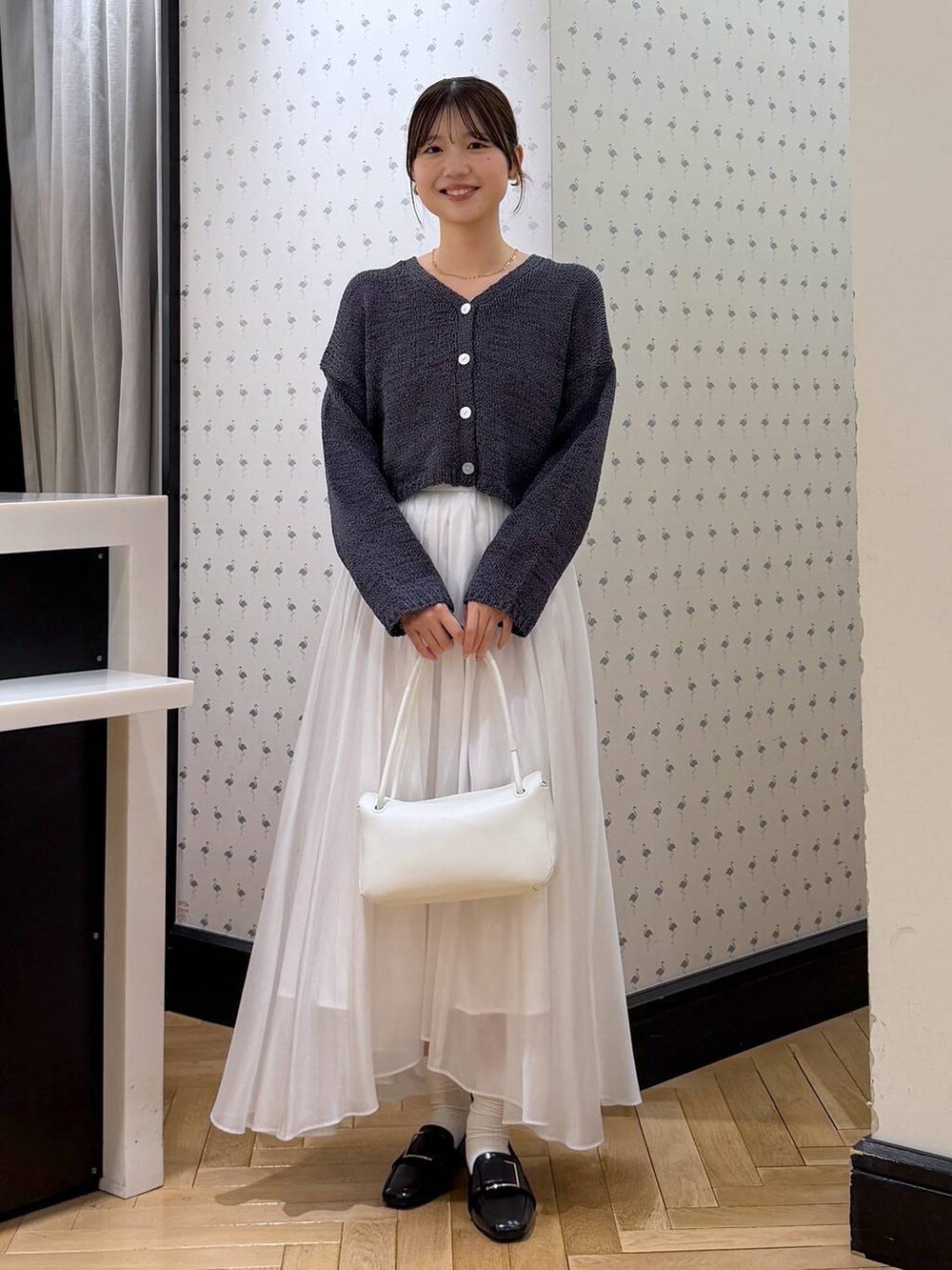 ホワイト系のスカート、ブラック系のローファー、ホワイト系のショルダーバッグを着用したレディースの冬コーディネートの4枚目の写真