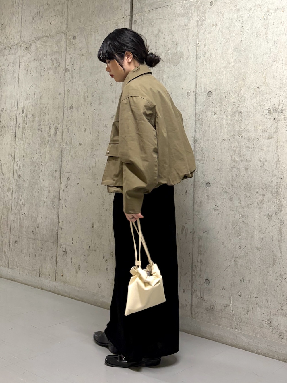 ブラック系のワンピース、グリーン系のブルゾン、ホワイト系のショルダーバッグを着用したレディースの春コーディネートの2枚目の写真