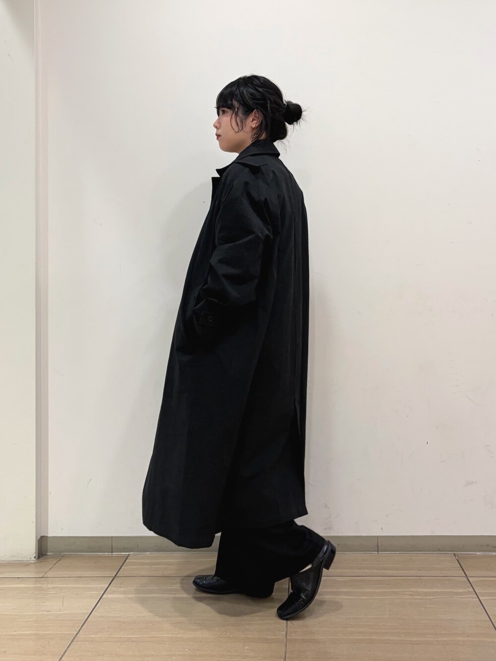 ブラック系のステンカラーコート、イエロー系のニット/セーター、ブラック系のその他パンツを着用したレディースの冬コーディネートの4枚目の写真